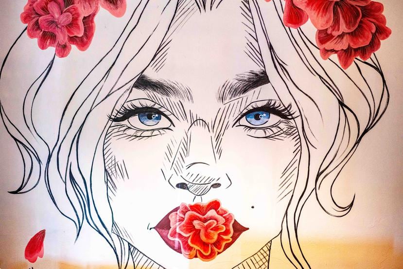 Un impresionante mural, en la entrada del local, del rostro de una joven mujer con una corona de flores rojas en su cabello y otras que brotan de su boca, es uno de los varios detalles del local.