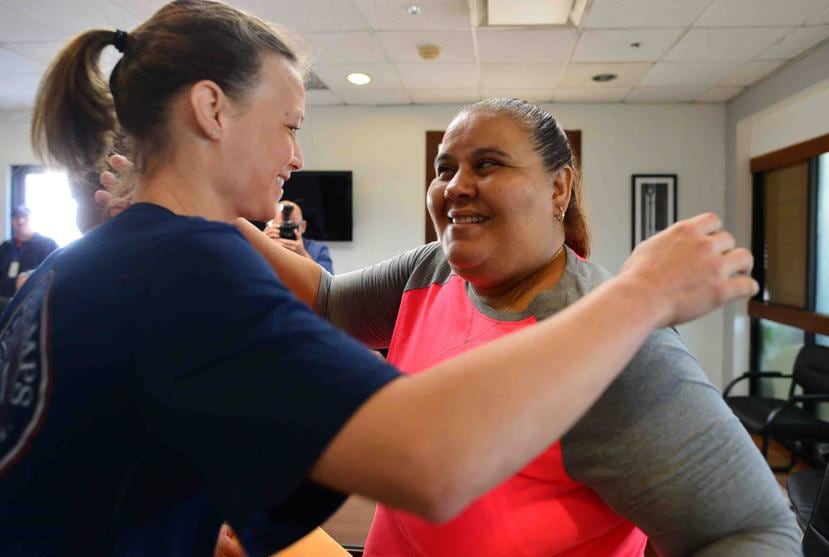 Courtney Thompson (centro) abraza a una de las personas que recibió la ayuda monetaria de la fundación Give It Back que la atleta creó junto con otras voleibolistas de los Estados Unidos.