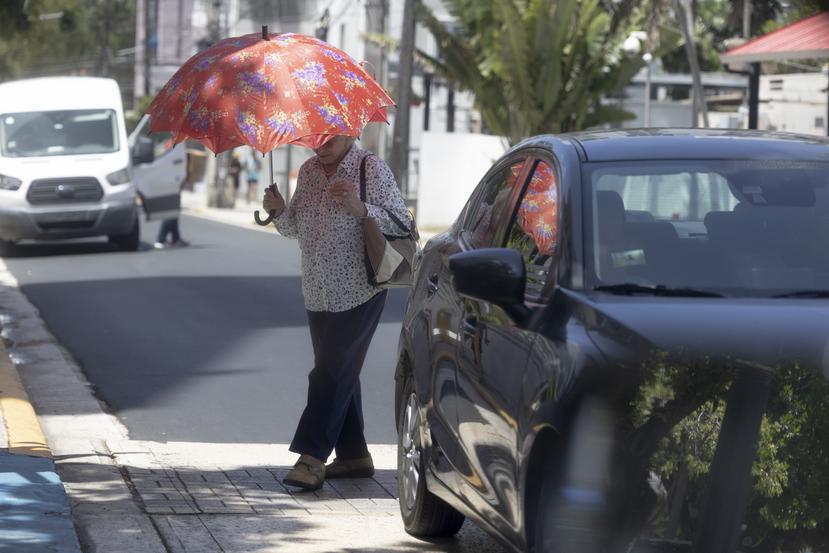 Imagen de archivo de una mujer protegiéndose del sol con una sombrilla en San Juan en momentos en que la capital estaba bajo aviso de calor extremo.