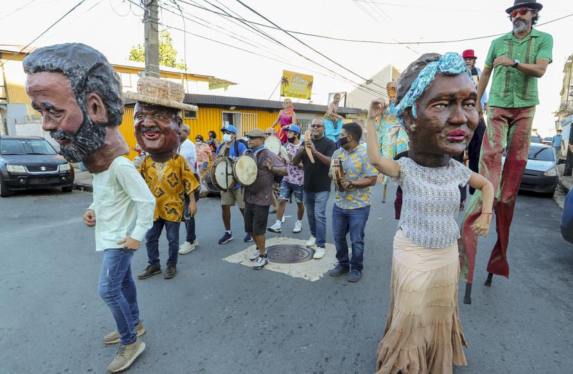 Zanqueros, pleneros y danzantes formaron la comparsa que recorrió las calles de la comunidad. A la derecha, el cabezudo de Elizam Escobar, a quien le dedicaron este primer encuentro.