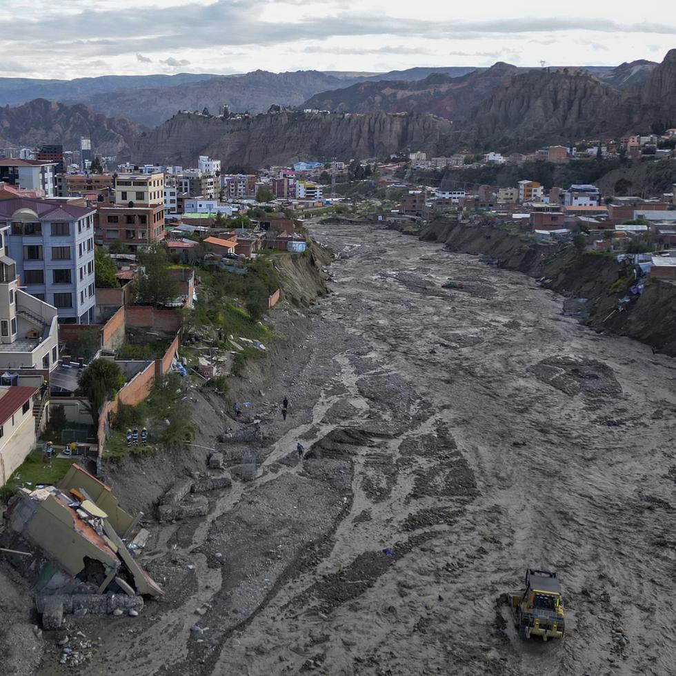 Trabajadores municipales utilizan maquinaria pesada para retirar fango del lecho del río Irpavi, donde lluvias persistentes dañaron varias viviendas en las márgenes, el jueves 22 de febrero de 2024, en La Paz, Bolivia. (AP Foto/Juan Karita)