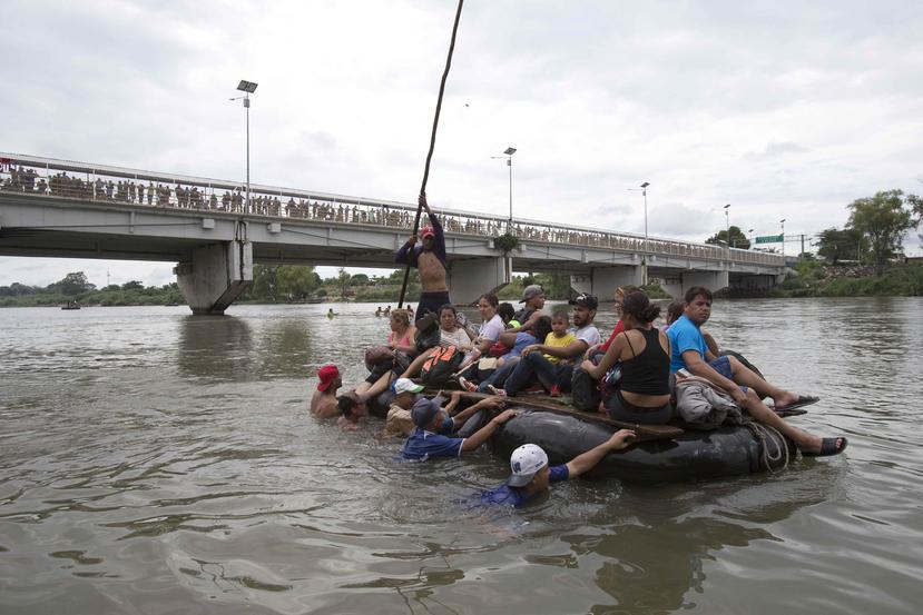 Un grupo de migrantes cruza el río Suchiate en una balsa hecha de neumáticos y tablones, en la frontera entre México y Guatemala. (AP)