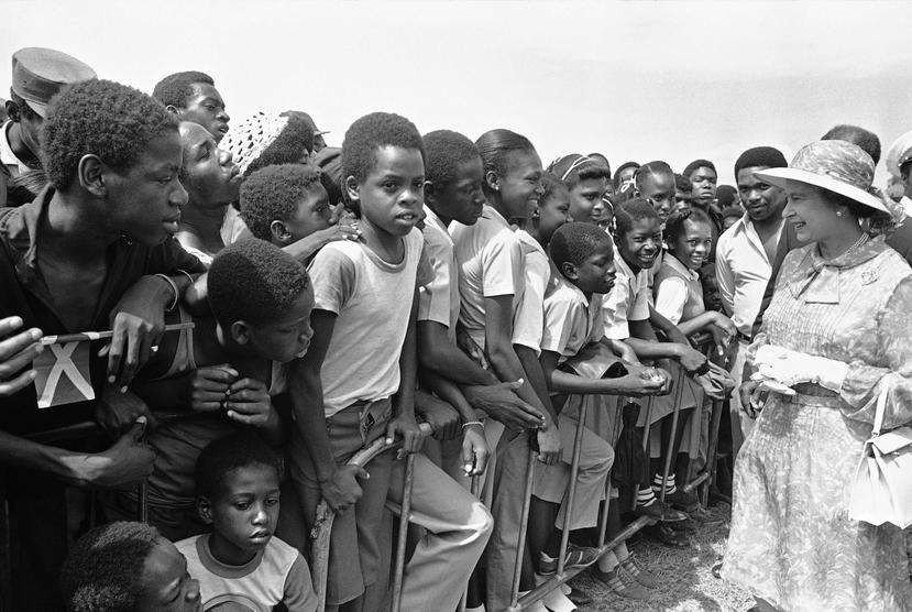 Escolares jamaicanos saludan a la reina Elizabeth II en el Monumento de los Héroes Nacionales en Kingston, Jamaica, el 14 de febrero de 1983, en el segundo día de la visita de la reina a la excolonia británica.