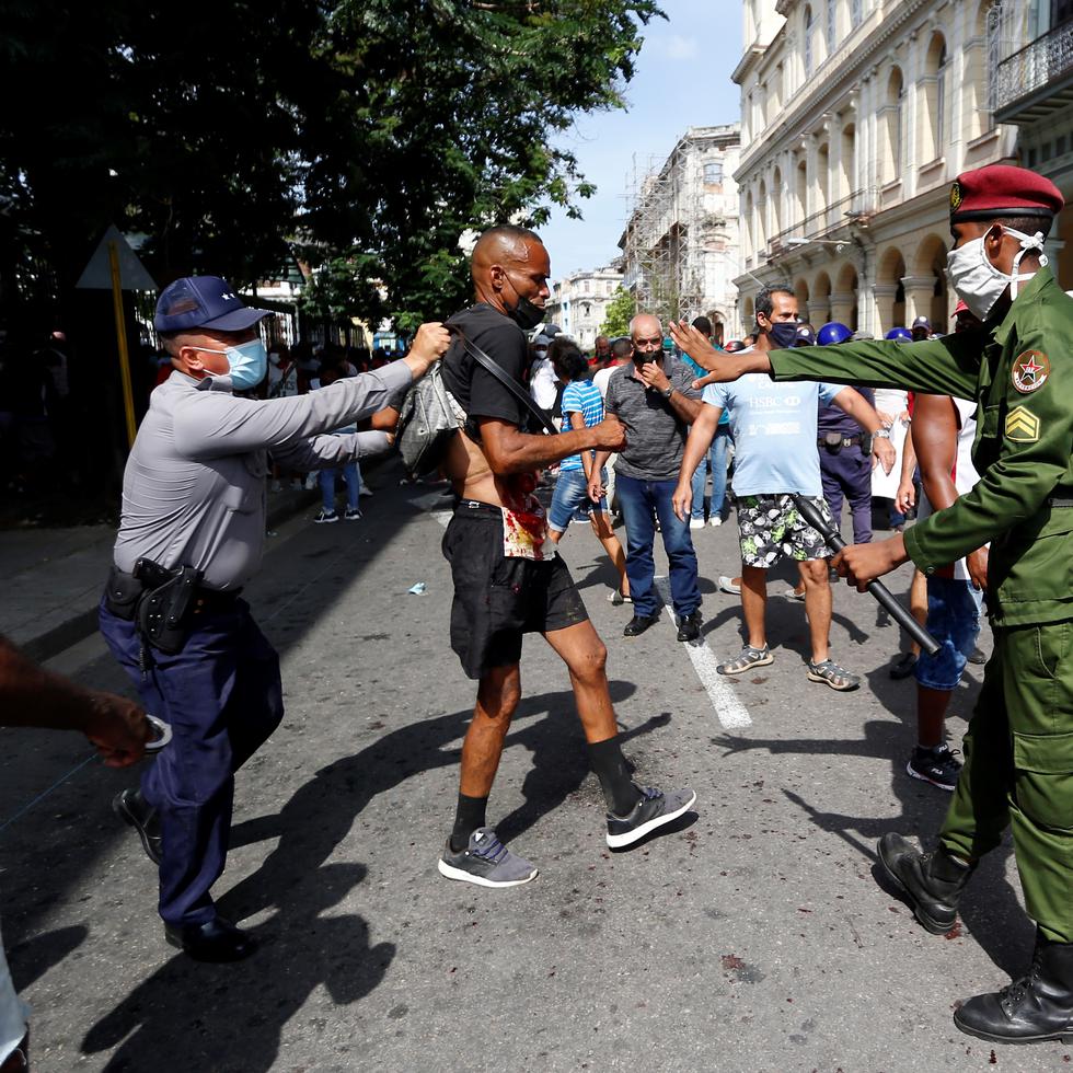 HAB15. LA HABANA (CUBA), 11/07/2021.- Policías arrestan a un hombre cuando personas se manifiestan hoy, en una calle en La Habana (Cuba). Cientos de cubanos salieron este domingo a las calles de La Habana al grito de "libertad" en manifestaciones pacíficas, que fueron interceptadas por las fuerzas de seguridad y brigadas de partidarios del Gobierno, produciéndose enfrentamientos violentos y arrestos. EFE/Ernesto Mastrascusa