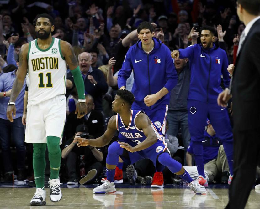 Jugadores de los Sixers celebran una jugada, mientras Kyrie Irving, de los Celtics, reacciona con frustración. (AP)