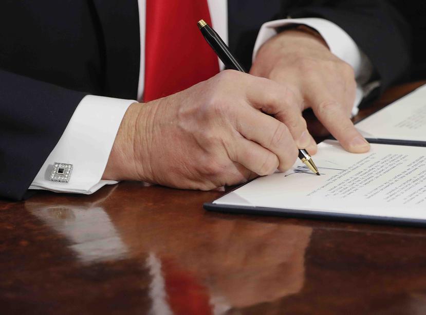 Trump firma las órdenes con plumas Cross que manda a fabricar especialmente y regala como recuerdo a los que asisten a las firmas. (AP)