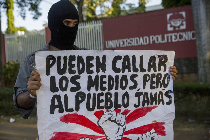 Un joven con una cartel protesta frente a las instalaciones de la universidad politécnica de Nicaragua. (EFE)