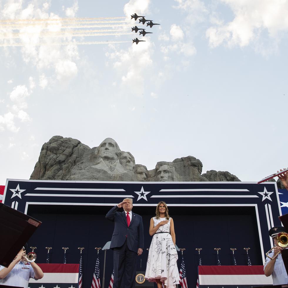 President Donald Trump, accompanied by first lady Melania Trump, stands during the national anthem with a flyover by the U.S. Navy Blue Angles at Mount Rushmore National Memorial, Friday, July 3, 2020, near Keystone, S.D. (AP Photo/Alex Brandon)