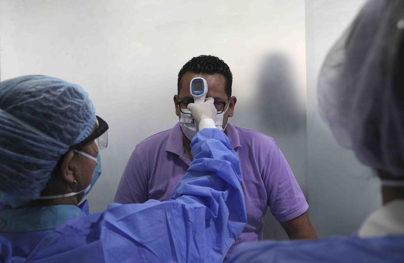 Personal sanitatorio toma la temperatura a un hombre en una pequeño centro médico en Lima, el miércoles 11 de marzo de 2020, como medida preventiva contra la propagación del nuevo coronavirus. La mayoría de la gente se recupera del COVID-19. (AP/Martín Me