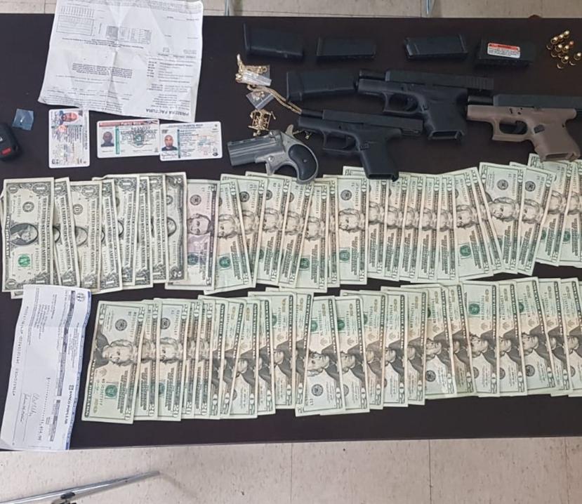 En la imagen el dinero en efectivo, el cheque y las armas de fuego ocupadas por la Policía en el vehículo de motor que era conducido por un hombre en Vega Baja y que huyó de las autoridades.