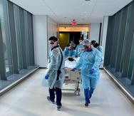 Enfermeros y personal del University Medical Center de New Orleans transportan en camilla a un paciente de COVID.