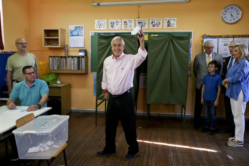 Sebastián Piñera levanta su papeleta electoral al momento de ir a votar en la segunda vuelta de las elecciones presidenciales de Chile. (AP / Esteban Félix)