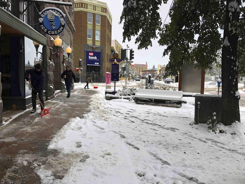 Varios ciudadanos limpiando la nieve a las afueras de comercios en Helena, Montana. (AP)