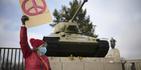 A woman shows a peace sign in front of a Russian WWII tank at the Soviet War Memorial at the bolevard 'Strasse des 17. Juni' alongside a rally against Russia's invasion of Ukraine in Berlin, Germany, Sunday, Feb. 27, 2022. (AP Photo/Markus Schreiber)