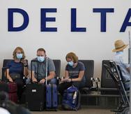 Personas están sentadas bajo el cartel de Delta en el Aeropuerto Internacional de Salt Lake City.