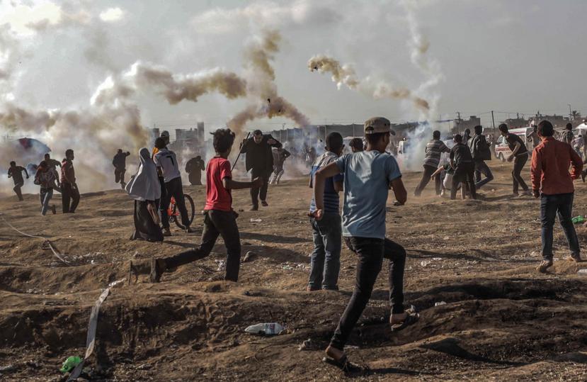 Manifestantes palestinos buscan refugio a causa de los gases lacrimógenos lanzados por los soldados israelíes durante unos enfrentamientos con Israel en la zona Este de la Franja de Gaza (EFE).