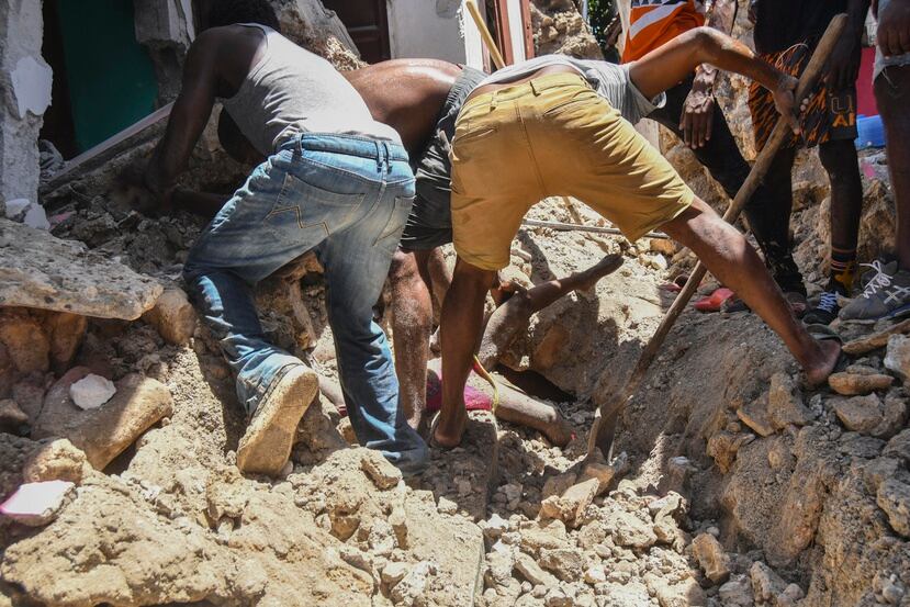 Un grupo de personas trabaja para recuperar el cuerpo de una niña enterrado por los escombros de una vivienda luego de un sismo en Haití.