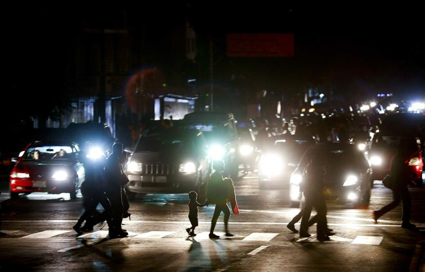 Residentes cruzan una calle en la oscuridad tras un apagón en Caracas, Venezuela. (AP Foto/Eduardo Verdugo)