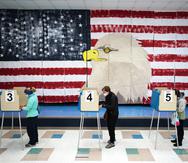 Tres personas emiten su voto al lado de un mural en la Robious Elementary School en Midlothian, Virginia.