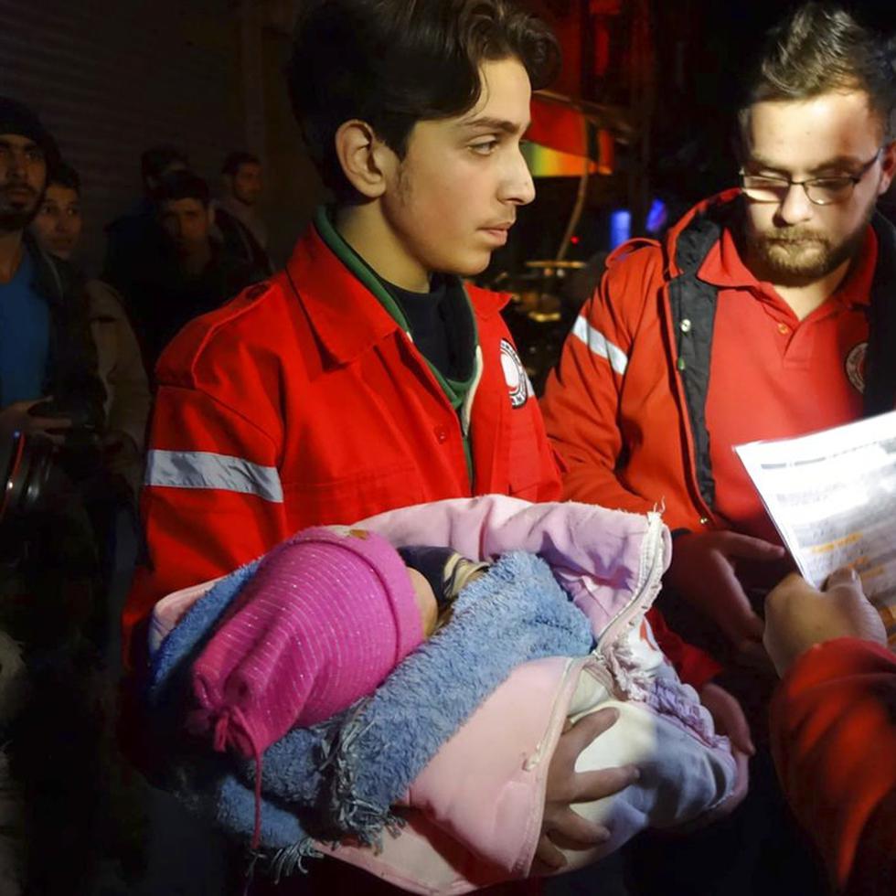 Personal del Comité Internacional de la Cruz Roja asiste a un bebé durante un desalojo en la ciudad de Guta, al este de Damasco, Siria (AP).