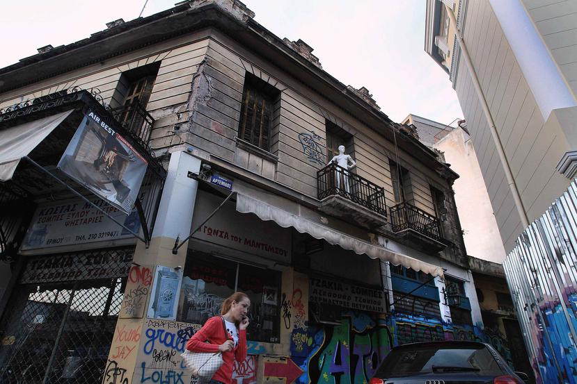Una mujer pasa cerca de un viejo eficio en el mercado central de Atenas.