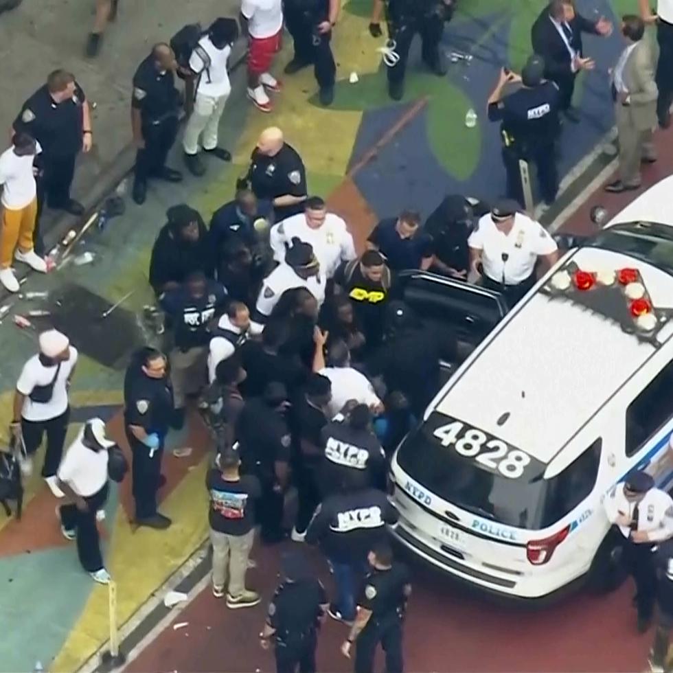 In this image taken from video provided by WABC-TV, internet influencer Kai Cenat, center, is helped into a New York Police vehicle near Union Square, Friday, Aug. 4, 2023, in New York. Police in New York City struggled to control a crowd of thousands of people who gathered in Manhattan's Union Square for the Internet personality's video game console giveaway that got out of hand. (WABC-TV via AP)