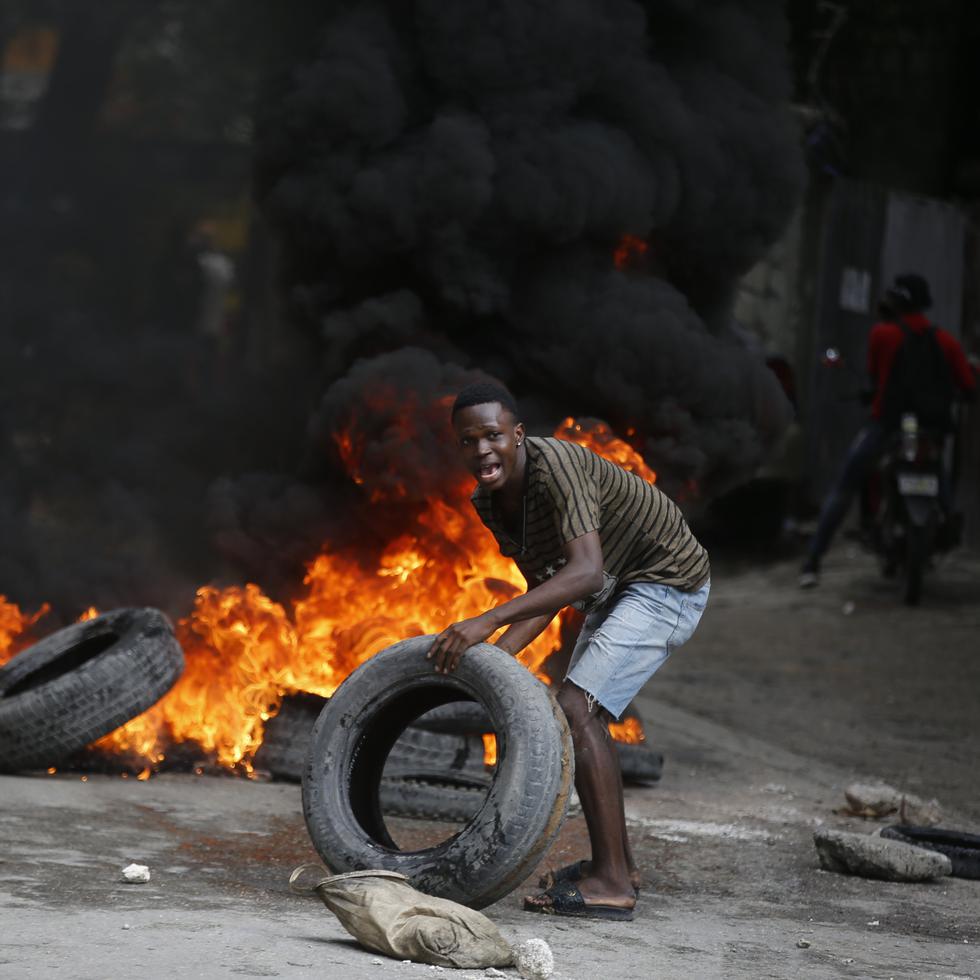 Un manifestante coloca neumáticos en una barricada en llamas durante una protesta para exigir la renuncia del primer ministro, Ariel Henry, en Puerto Príncipe, Haití, el 7 de febrero de 2024.