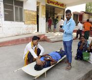 Familiares cuidan a una paciente acostada en una camilla afuera de un hospital del distrito de Ballia, en India.