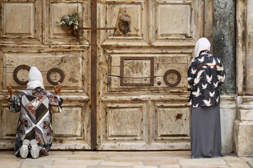 Unas mujeres rezan frente a una iglesia cerrada en Jerusalén, el domingo 5 de abril de 2020. (AP)