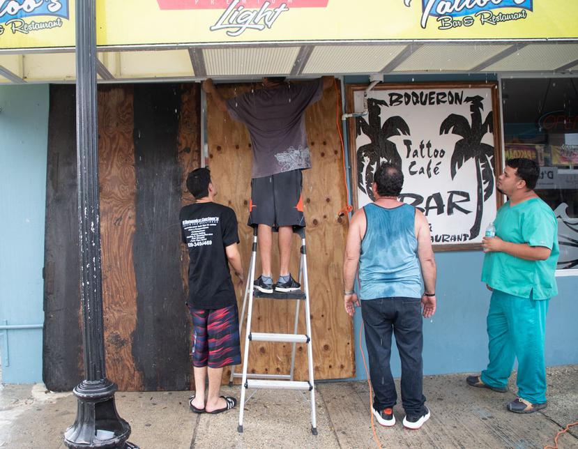 Empleados del Boquerón Tattoo Cafe Bar colocan paneles de madera para proteger las puertas del establecimiento.