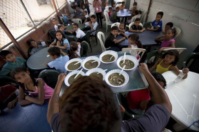 Un grupo de niños miran su comida gratis en un comedor social auspiciado por la oposición en Caracas, Venezuela. (AP)