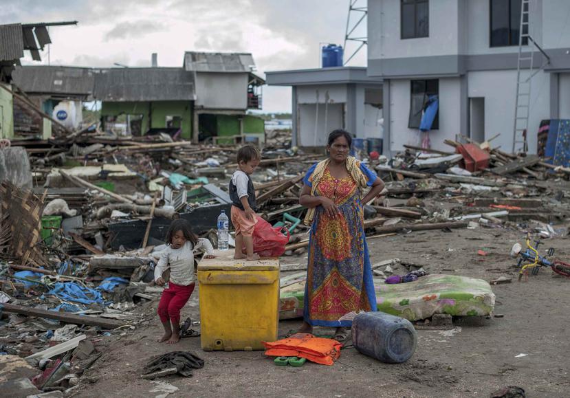 Una mujer y sus hijos inspecionan los escombros dejados por el tsunami que afectó el poblado de Sumur, en Indonesia. (AP)