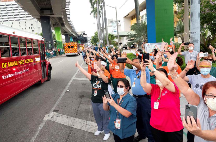 Trabajadores de la salud observan el paso del desfile en honor de los trabajadores que enfrentan el coronavirus, el miércoles 20 de mayo de 2020, en Miami (Estados Unidos). (EFE)