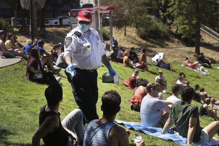 FILE - San Francisco Police Auxiliary Law Enforcement Response Team (ALERT) volunteer David Flynn offers face masks to help prevent the spread of the coronavirus at Dolores Park in San Francisco, Sunday, May 24, 2020. California is creating roving "strike teams" drawn from seven state agencies that will enforce state guidelines designed to slow the spread of the coronavirus, Gov. Gavin Newsom said Wednesday, July, 1, 2020. The teams include representatives from the California Highway Patrol; the Division of Occupational Safety and Health, known as CalOSHA; the Department of Alcohol Beverage Control; the Board of Barbering &amp; Cosmetology; the departments of Business Oversight and Consumer Affairs. (AP Photo/Jeff Chiu, File)