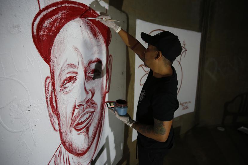 El artista Julián Castillo pinta un retrato del cantante puertorriqueño René Pérez, Residente, con sangre humana, en el barrio Siloé, en Cali, Colombia.