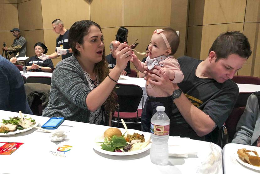 Kameron Davis y  Nick Daily disfrutan de una comida de Acción de Gracias junto a su hija Marley Daily durante una celebración comunitaria en la Universidad de California State en Chico. (AP)