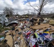 ARCHIVO - Gente entre los restos de un tornado nocturno en Sullivan, Indiana, el 1 de abril de 2023. (AP Foto/Doug McSchooler, Archivo)