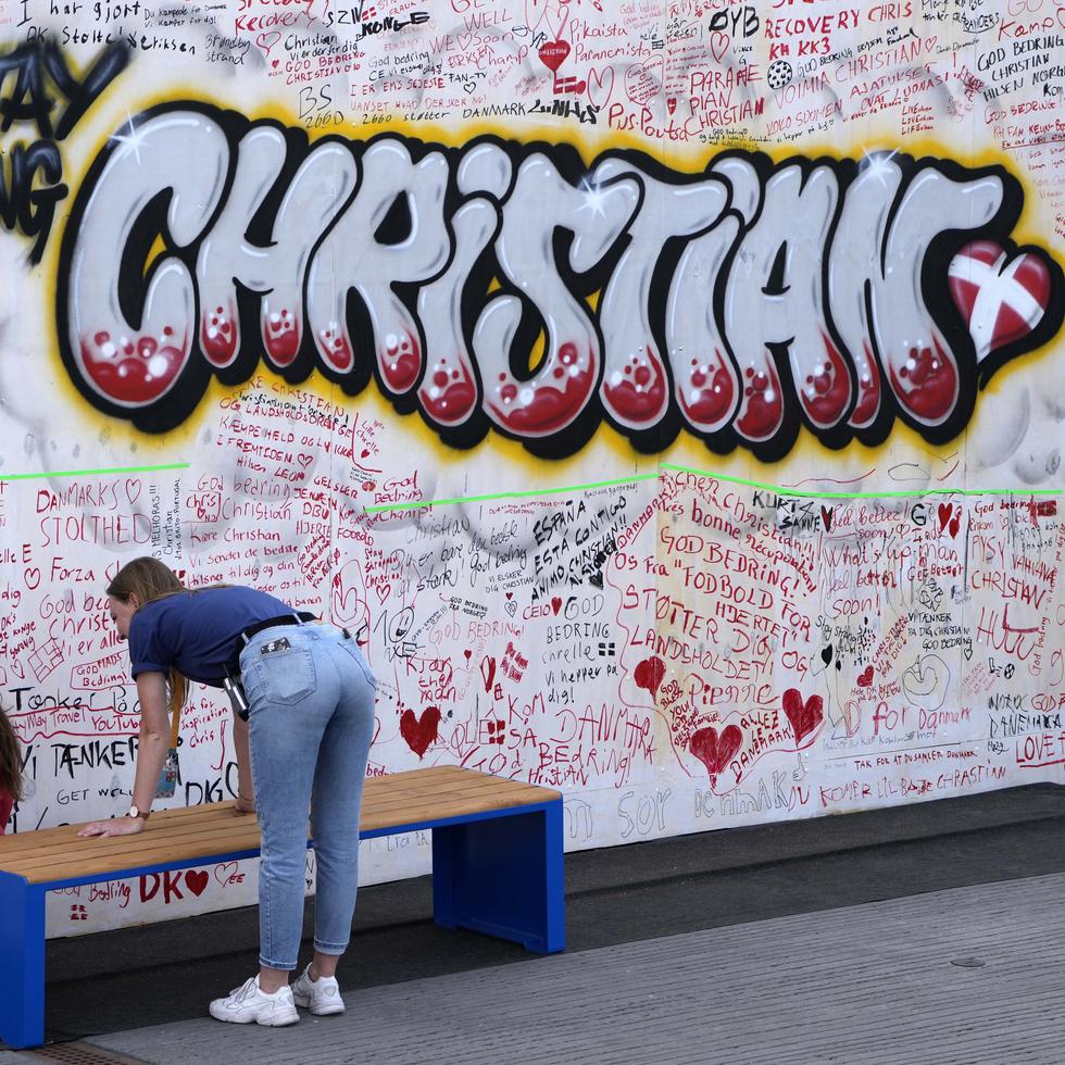 Dos personas dejan sus buenos deseos en un grafiti para el jugador de la selección de Dinamarca Christian Eriksen en una pared de la fanzone de la Eurocopa 2021 en Copenhague, Dinamarca.