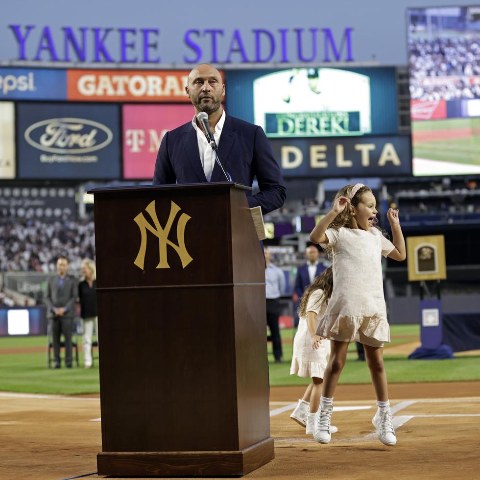 Derek Jeter se dirige a los fanáticos de los Yankees mientras que su hija mayor Bella Raine luce inquieta en el terreno.