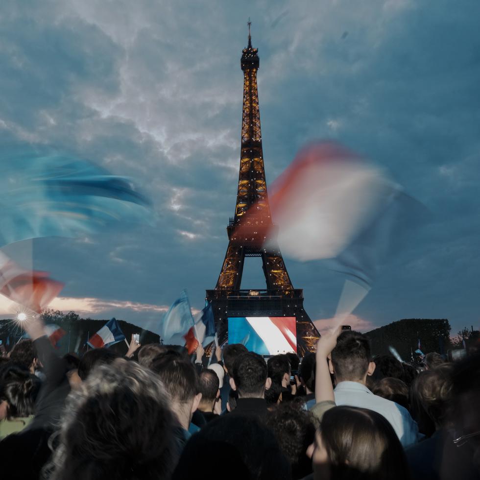 Supporters of French President Emmanuel Macron wave the national flag as the Eiffel Tower twinkles in Paris, France, Sunday, April 24, 2022. Polling agencies projected that French President Emmanuel Macron comfortably won reelection Sunday in the presidential runoff, offering French voters and the European Union the reassurance of leadership stability in the bloc's only nuclear-armed power as the continent grapples with Russia's invasion of Ukraine. (AP Photo/Thibault Camus)