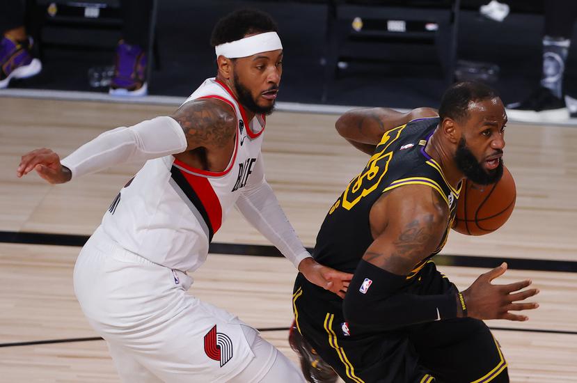 El jugador de Los Lakers LeBron James, derecha, intenta encestar mientras Carmelo Anthony de los Trail Blazers de Portland defiende.
