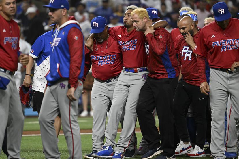 Ricky Bones, coach de lanzadores, y el cuerpo médico de Puerto Rico ayuda a Edwin Díaz a salir del terreno tras lesionarse la rodilla derecha.