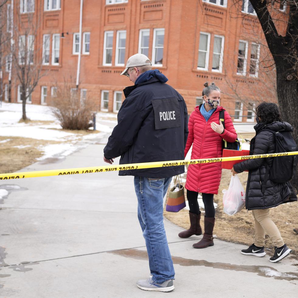 Un oficial de la policía escolta a dos personas en la Escuela Elemental University Hill que queda frente al campus de la Universidad de Colorado.