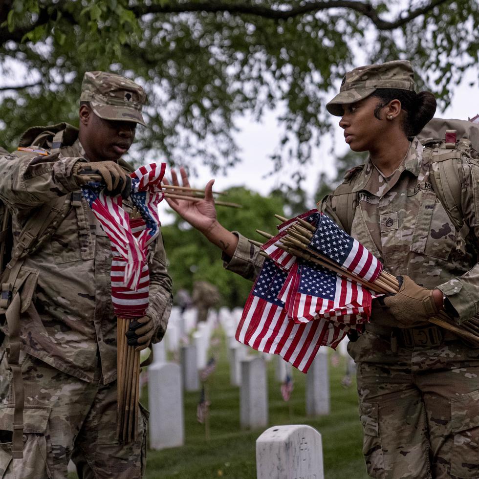 Miembros del 3er Regimiento de Infantería de EE.UU., también conocido como La Vieja Guardia, colocan banderas delante de cada lápida para el "Flags-In" al amanecer en el Cementerio Nacional de Arlington en Arlington, el jueves 25 de mayo de 2023, para honrar a los héroes militares caídos.