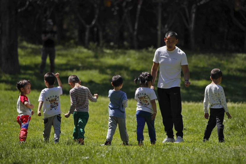 Niños acompañados por un hombre juegan en un parque público, mientras escuelas infantiles y primarias siguen cerradas por la restricciones contra el nuevo coronavirus en Beijing. (AP)