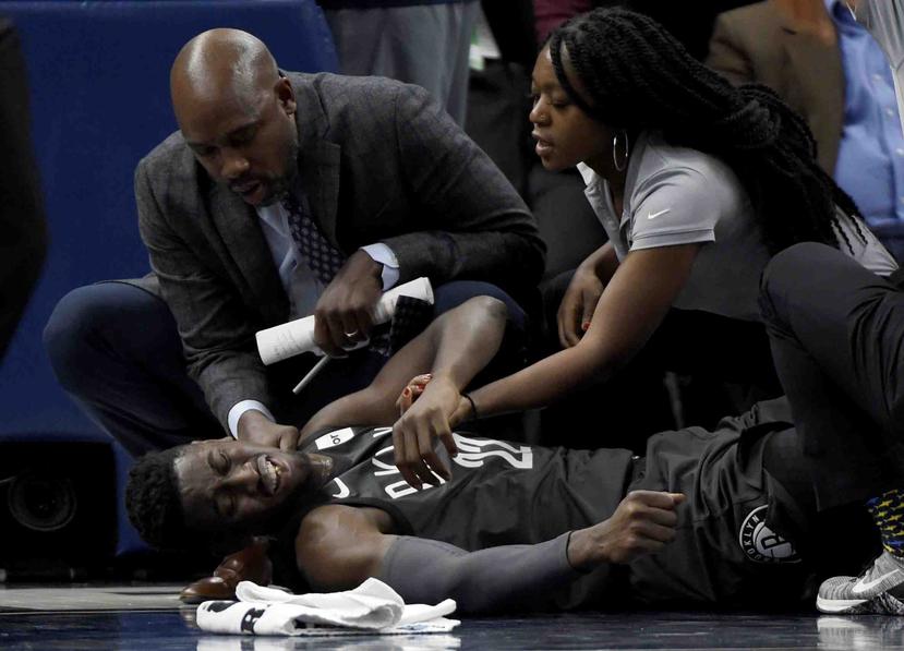 El escolta de los Nets de Brooklyn, Caris LeVert (22), es atendido en la duela luego de sufrir una lesión en el tobillo. (AP)