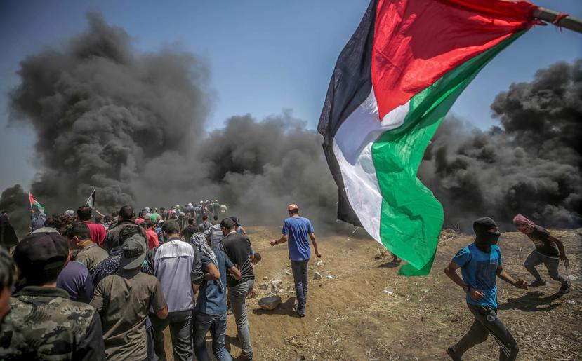 Manifestantes corren para protegerse del gas lacrimógeno lanzado por soldados israelíes durante unas protestas en la frontera de Gaza en Israel (EFE/ Mohammed Saber).