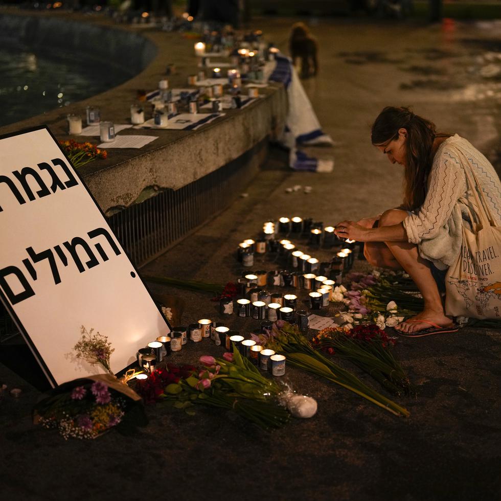 Una mujer enciende una vela en honor a las víctimas del ataque de Hamas durante una vigilia en Dizengoff en el centro de Tel Aviv el viernes 13 de octubre del 2023. (AP Foto/Francisco Seco)