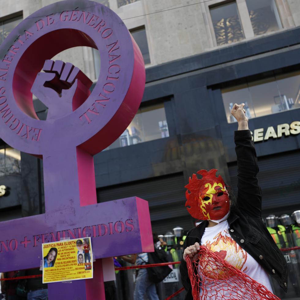 Una mujer enmascarada levanta el puño durante una marcha el lunes 8 de marzo de 2021  para conmemorar el Día Internacional de la Mujer y protestar contra la violencia de género, en la Ciudad de México. (AP Foto/Rebecca Blackwell)