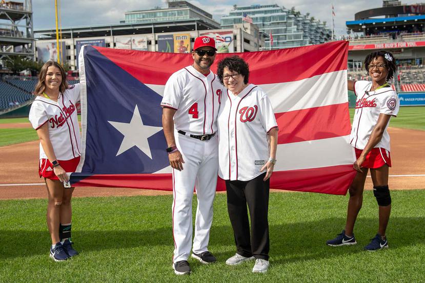 El dirigente de los Nationals Dave Martínez y la jueza del Tribunal Supremo de Estados Unidos, Sonia Sotomayor, posan juntos con la bandera de Puerto Rico a sus espaldas. (Suministrada / Nationals de Washington)